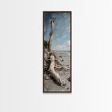 Framed Canvas Print Skinny Art of a Weathered Driftwood Tree Trunk on a Sandy Shore with a Calm Ocean Backdrop, Ideal Tall Art for Coastal Decor